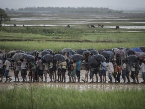 In this file photo taken on October 6, 2017, Rohingya Muslim refugees wait in line under the rain during a food distribution under at Nayapara refugee camp in Bangladesh's Ukhia district.