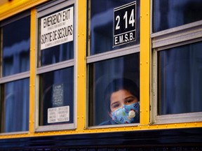 A student peers through the window of a school bus as he arrives at the Bancroft Elementary School in Montreal, on August 31, 2020.