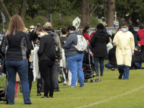 A healthcare worker walks along a line of hundreds of people waiting outside a COVID-19 testing facility in Ottawa, Sept. 15, 2020.