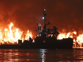 A boat is seen at a fire at Pier Park along the Fraser River in New Westminster, B.C. on Sunday, September 13, 2020. A waterfront park along the Fraser River in New Westminster, B.C., has been extensively damaged by a major fire. New Westminster Mayor Jonathan Cote called the situation at Pier Park "devastating" in a social media message posted late Sunday night.