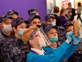 A museum employee wearing a protective visor takes a photo with Russian National Guards (Rosgvardia)  during the Artlife Fest International contemporary art festival in Moscow on September 21, 2020, amid the crisis linked with the covid-19 pandemic caused by the novel coronavirus.