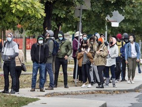 People wearing masks wait in line for Covid-19 Testing at Toronto's St. Joseph's Health Centre during the Covid-19 pandemic, Friday October 2, 2020.