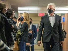 Gilbert Rozon walks past several women wearing #MeToo masks at the Palais de Justice Oct. 13, 2020, before his trial on rape charges.