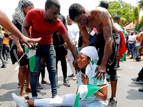 A Nigerian woman based in South Africa weep as others comfort her during a protest outside their embassy in Pretoria on October 21, 2020 in solidarity with Nigerian youth who are demanding an end to police brutality in the form of The Nigerian Police Force Unit,  Special Anti-Robbery Squad (SARS).