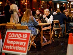 People drink at the outside tables of a cafe in Soho, in central London on September 23, 2020.