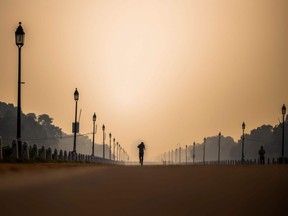 A man jogs along Rajpath street during a smoggy morning in New Delhi on October 15, 2020.