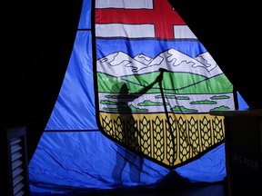 A worker steams the wrinkles from a large Alberta flag at the site of a United Conservative Party rally in Calgary on April 16, 2019.