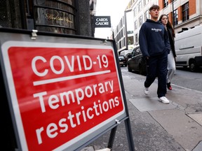A coronavirus disease sign is seen as people walk, in the Soho area, in London Britain October 15, 2020.