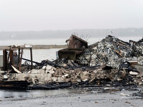 A person looks at the remains of a lobster pound after it burnt in Middle West Pubnico, N.S., on Oct. 17.