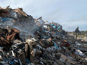 Smoke rises in the air as a RCMP officer walks around the remains of a lobster pound that was destroyed by a fire in Middle West Pubnico, N.S., on Oct. 17.