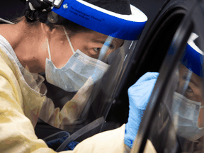 A nurse performs a test on a patient at a drive-in COVID-19 clinic in Montreal.