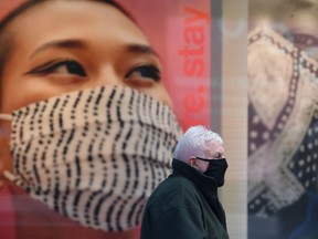 A pedestrian wearing a facemask sits by advertising for facemasks in central Liverpool, north west England on October 14, 2020. PHOTO BY PAUL ELLIS/AFP.