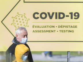 People wear face masks outside a COVID-19 testing clinic in Montreal on Oct.11, 2020, as Canada battles a second wave of the coronavirus pandemic.