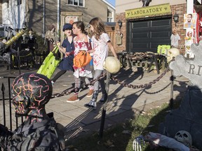 Jessica Gavin-Leroux, centre, and sisters Lilliana and Kayla Frigon ‘Trick or Treat’ outside a house on Halloween in Montreal, Saturday, October 31, 2020, as the COVID-19 pandemic continues in Canada and around the world.