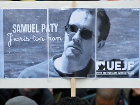 A person holds a placard with the portrait of history teacher Samuel Paty as people gather in Paris on October 18, 2020, in a show of solidarity and defiance.