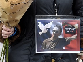 A woman holds a photo of Samuel Paty at Place de la Liberte in Lille, France, on Oct. 18, 2020, in homage to the civics teacher two days after he was beheaded on the street by a Muslim extremist who was then shot dead by police.