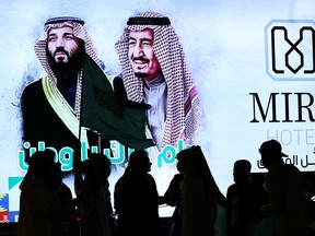 People walk past a poster of Saudi Arabia's King Salman bin Abdulaziz Al Saud and Crown Prince Mohammed bin Salman as they celebrate Saudi Arabia's 90th annual National Day in Riyadh on Sept. 23, 2020.