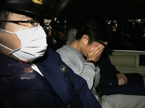 Suspect Takahiro Shiraishi (C) covers his face with his hands as he is transported to the prosecutor's office from a police station in Tokyo on November 1, 2017.