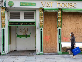 A woman walks past a boarded up bar in Dublin on Oct. 21, 2020 as Ireland prepares to enter a second national lockdown to stem the spread of the virus that causes COVID-19.