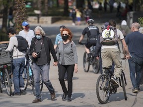 People wear face masks as they walk in a city park in Montreal, Saturday, Oct. 10, 2020, as the COVID-19 pandemic continues in Canada and around the world.