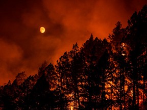 The Moon  hues orange as the Glass Fire begins to descend into the valley after ravaging the hills as night falls on Napa Valley, California on September 27, 2020.