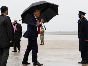 U.S. President Donald Trump walks without a mask and carries an umbrella while boarding Air Force One as he departs Washington for travel to Florida, his first campaign trip since being treated for the coronavirus disease (COVID-19), at Joint Base Andrews, Maryland, U.S., October 12, 2020.