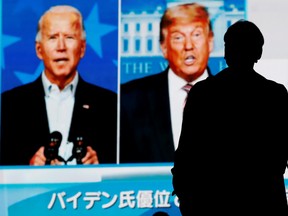 A passerby is silhouetted against a big screen showing reports on 2020 U.S. presidential election in Tokyo, Japan November 6, 2020.