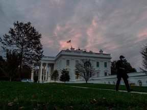 A Secret Service agent walks down a path as the sun rises over the White House in Washington, DC on November 1, 2020.