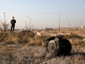 A police officer stands guard as debris is seen from an Ukrainian plane that crashed in Shahedshahr, Iran, on Jan. 8.