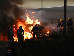 Fire marshals put out a fire on Haas F1's French driver Romain Grosjean's car during the Bahrain Formula One Grand Prix at the Bahrain International Circuit in the city of Sakhir on November 29, 2020.