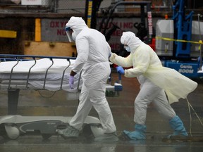 Medical personnel move a deceased patient to a refrigerated truck serving as make shift morgues at Brooklyn Hospital Center on April 09, 2020 in New York City.