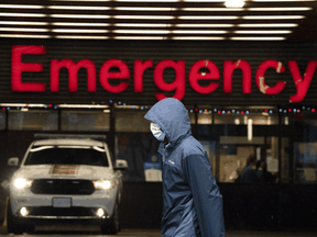 A person wears a protective face mask to help prevent the spread of COVID-19 as they walk past the emergency department of the Vancouver General Hospital, Wednesday, Nov. 18, 2020.