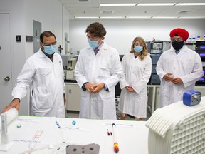 Prime Minister Justin Trudeau, second from left, along with two of his cabinet ministers, tours a National Research Council of Canada facility in Montreal on Aug. 31.