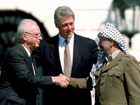 U.S. President Bill Clinton, centre, looks on as Israeli Prime Minister Yitzhak Rabin, left, and Palestine Liberation Organization leader Yasser Arafat shake hands after the signing of the Israeli-PLO peace accord at the White House in Washington, D.C., on Sept. 13, 1993.