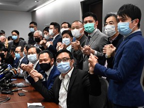 Pro-democracy lawmakers join hands at the start of a press conference in Hong Kong on Nov. 11, 2020, after four of them were stripped of their seats after China gave the city the power to disqualify politicians deemed a threat to national security. The remaining pro-democracy legislative council members resigned en masse in protest.