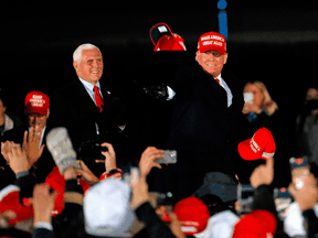 U.S. President Donald Trump, followed by Vice President Mike Pence, throws hats to the crowd during his final Make America Great Again rally of the 2020 U.S. Presidential campaign at Gerald R. Ford International Airport on November 2, 2020, in Grand Rapids, Michigan.