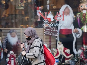 People wear face masks as they walk by a Christmas store in Montreal, Sunday, November 8, 2020, as the COVID-19 pandemic continues in Canada and around the world.