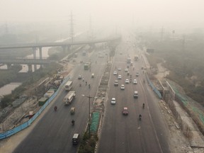 Traffic moves along a highway shrouded in smog in New Delhi, India, November 15, 2020