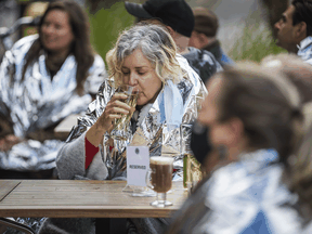 Wearing supplied thermal blankets, patrons at a Toronto pub have a drink on the patio in late October.