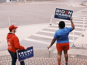 Robby Thurston, left, and Tamika Morris, right, volunteers for the rival Trump and Biden campaigns, wave signs in St. Petersburg, Fla.., a state where pollsters incorrectly predicted a close victory for Joe Biden.