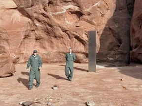 Utah public officials walk around a random metal monolith, mysteriously planted in the remote desert.