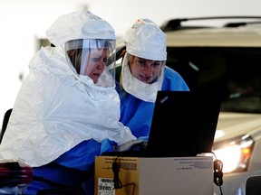 Healthcare workers wearing powered air purifying respirator (PAPR) hoods process COVID-19 test samples at a drive-thru testing site operated by Avera Health inside the former Silverstar Car Wash, as the coronavirus disease (COVID-19) outbreak continues in Sioux Falls, South Dakota, U.S., October 28, 2020.