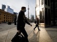 Pedestrians wearing protective masks walk through downtown Toronto on Monday, Nov. 23, 2020. Canada's largest province ordered a lockdown in Toronto and one of its suburbs, a declaration that forces shopping malls, restaurants and other businesses to close their doors to slow a second wave of coronavirus cases.