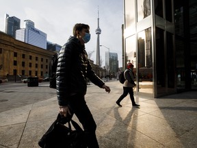 Pedestrians wearing protective masks walk through downtown Toronto on Monday, Nov. 23, 2020. Canada's largest province ordered a lockdown in Toronto and one of its suburbs, a declaration that forces shopping malls, restaurants and other businesses to close their doors to slow a second wave of coronavirus cases.