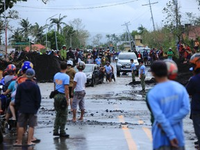 Residents gather along road damaged by heavy rains brought by the super Typhoon Goni after it hit the town of Malinao, Albay province, south of Manila on November 1, 2020.