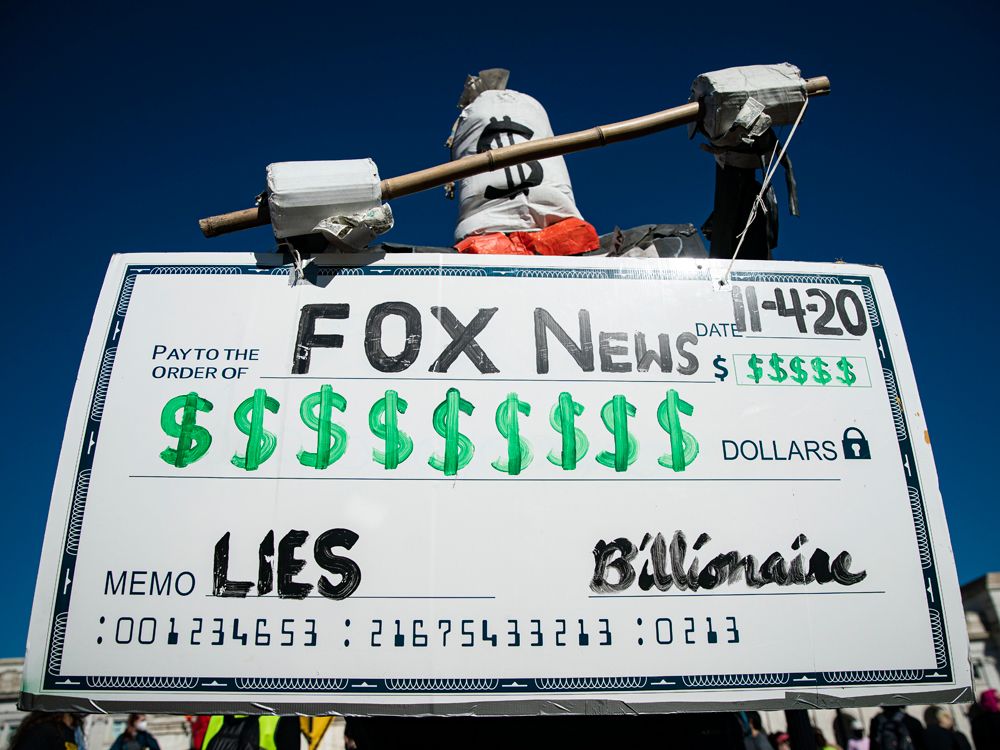 A figure holds a symbolic check during a protest from Union Station to the Fox News offices, on Nov.  4, 2020 in Washington, DC 