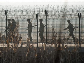 North Korean soldiers patrol next to the border fence near the town of Sinuiju across from the Chinese border town of Dandong on February 10, 2016.