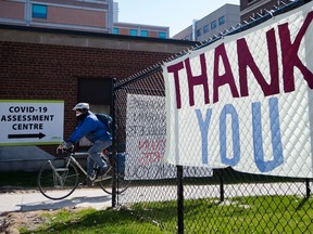 A man rides his bicycle at a COVID-19 assessment centre as a thank you sign for healthcare workers is on display at a hospital in Toronto on Wednesday, April 22, 2020.