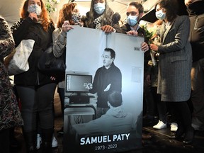 Relatives and colleagues hold a picture of Samuel Paty during the 'Marche Blanche' in Conflans-Sainte-Honorine, northwest of Paris, on Oct. 20, 2020.