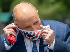 In this file photo taken on July 01, 2020 Rudy Giuliani, attorney for US President Donald Trump, puts on a mask after speaking at the White House in Washington, DC.